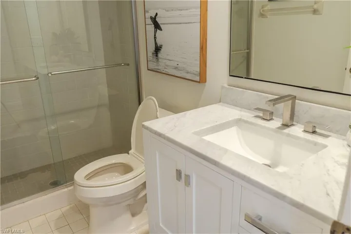 Bathroom with toilet, a shower stall, tile patterned flooring, and vanity