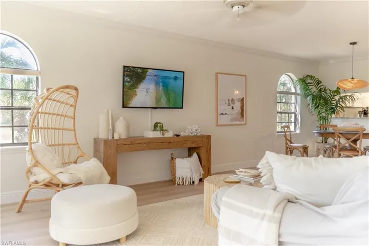 Living area featuring light wood-style flooring, baseboards, crown molding, and ceiling fan