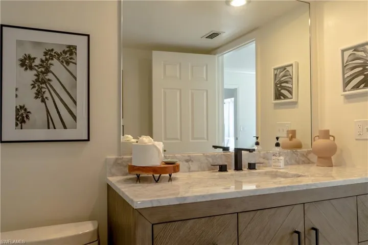 Bathroom with toilet, vanity, and visible vents