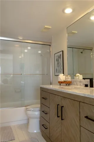 Bathroom with visible vents, bath / shower combo with glass door, toilet, vanity, and tile patterned floors