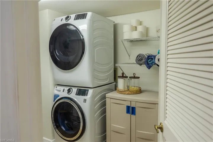 Washroom featuring cabinet space and stacked washer and clothes dryer