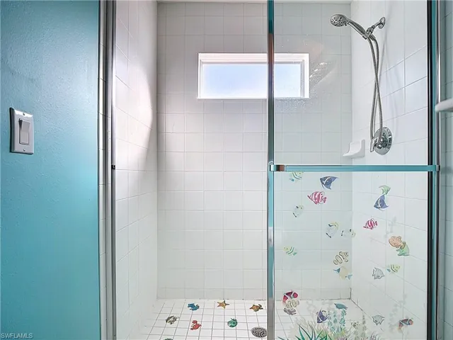 Bathroom with a shower stall and a textured wall