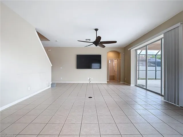 Unfurnished living room featuring arched walkways, light tile patterned floors, and a ceiling fan