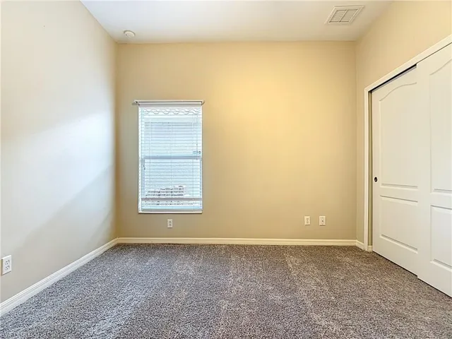 Unfurnished bedroom featuring dark carpet and a closet