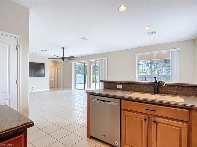 Kitchen with stainless steel dishwasher, a ceiling fan, light tile patterned floors, plenty of natural light, and recessed lighting