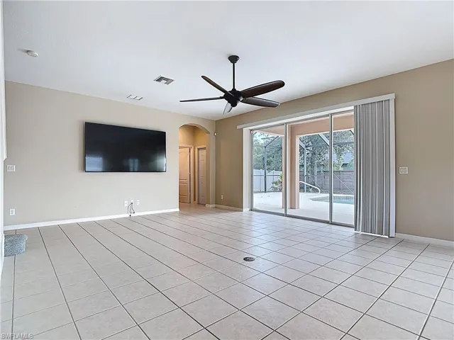 Unfurnished living room featuring arched walkways, light tile patterned flooring, and ceiling fan