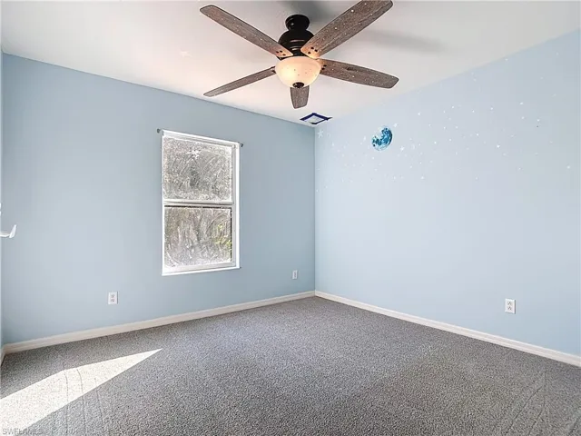 Carpeted spare room featuring baseboards and ceiling fan