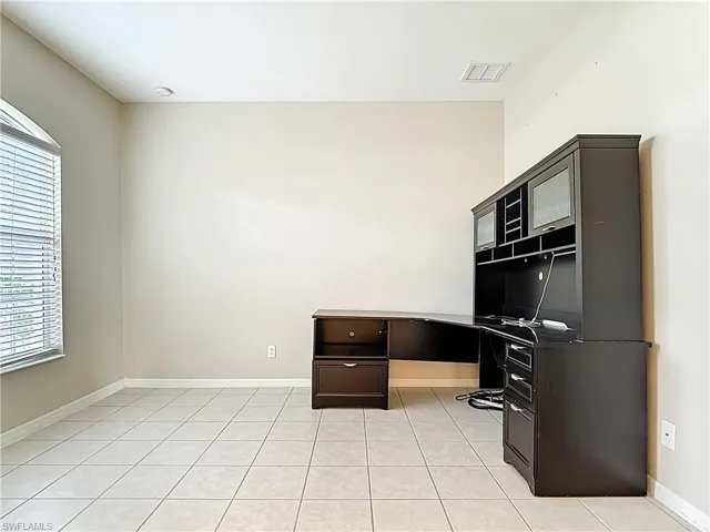 Unfurnished office with light tile patterned flooring and built in study area