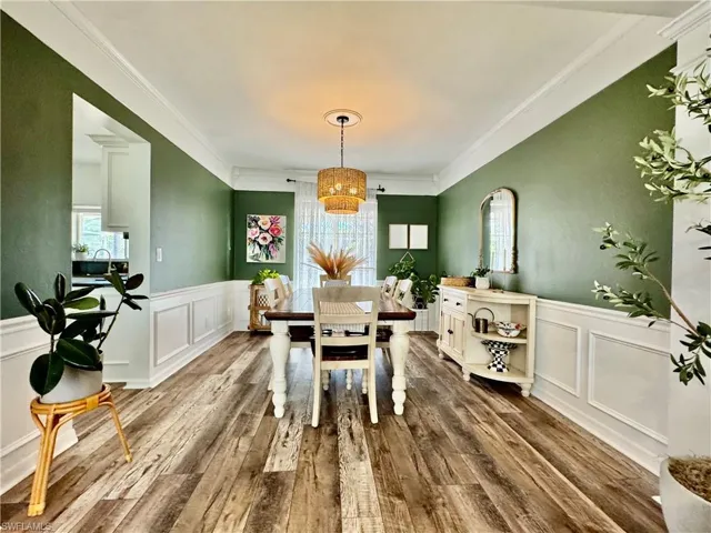 Dining area featuring a decorative wall, healthy amount of natural light, wainscoting, crown molding, and a chandelier