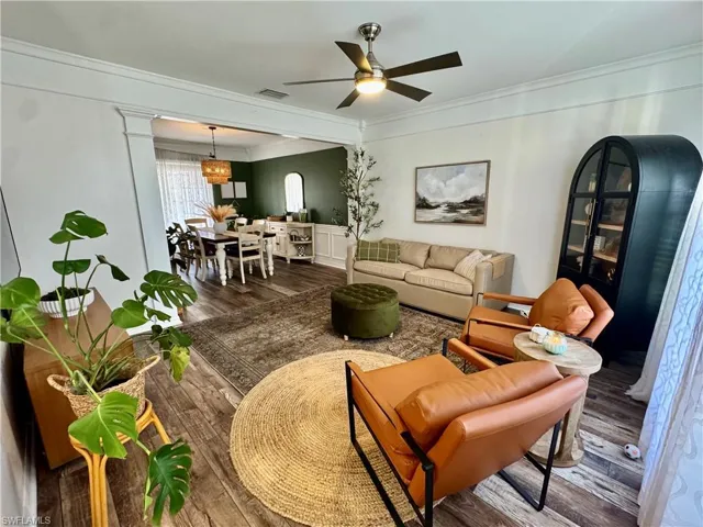 Living room with wood finished floors, crown molding, a ceiling fan, and a chandelier