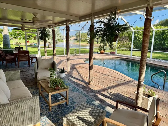 Swimming pool with a ceiling fan, a patio area, and glass enclosure