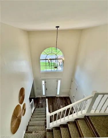Foyer with a chandelier, wood finished floors, and stairs