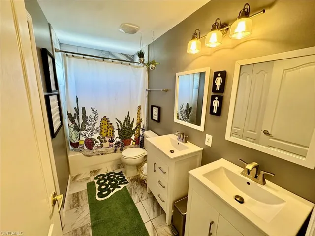 Bathroom with two vanities and shower / tub combo with curtain