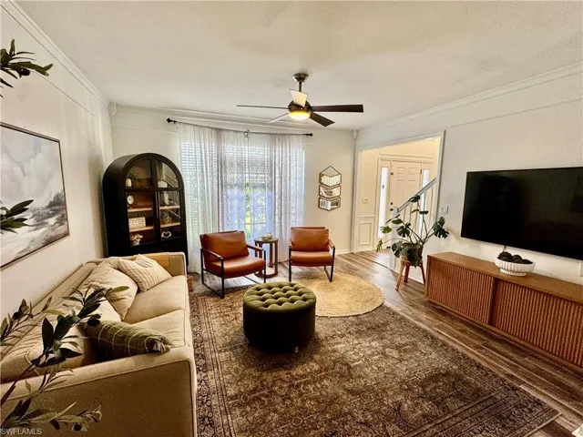 Living area featuring crown molding, wood finished floors, and a ceiling fan