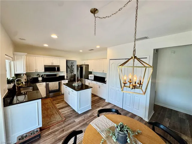 Kitchen featuring stainless steel appliances, dark countertops, a chandelier, recessed lighting, and white cabinetry