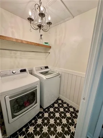 Laundry area with washing machine and clothes dryer, tile patterned floors, and wainscoting