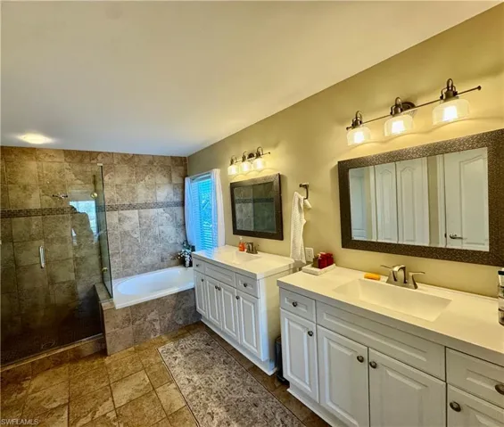 Bathroom with two vanities, a garden tub, and a stall shower