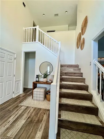 Staircase with wood finished floors and a high ceiling