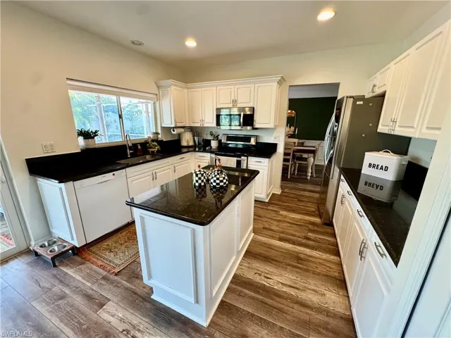 Kitchen featuring stainless steel appliances, white cabinets, dark wood-type flooring, a center island, and recessed lighting