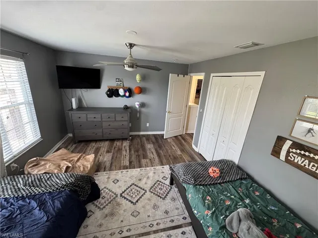 Bedroom featuring wood finished floors, multiple windows, a closet, and a ceiling fan