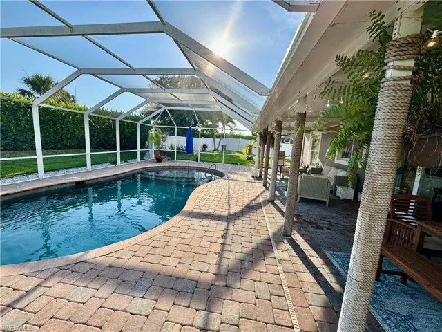 View of pool featuring a patio, an outdoor living space, a fenced backyard, and glass enclosure