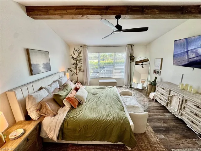 Bedroom featuring dark wood-type flooring, beam ceiling, and ceiling fan