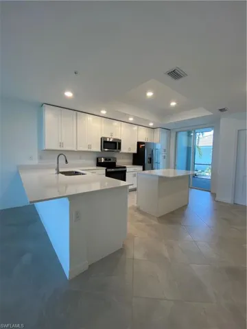 Kitchen with stainless steel stove, white cabinets, sink, and fridge
