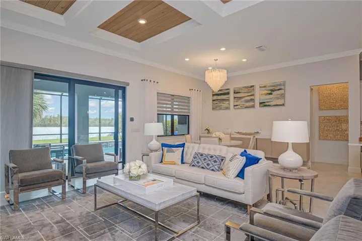 Living room with beamed ceiling, coffered ceiling, ornamental molding, a chandelier, and wooden ceiling
