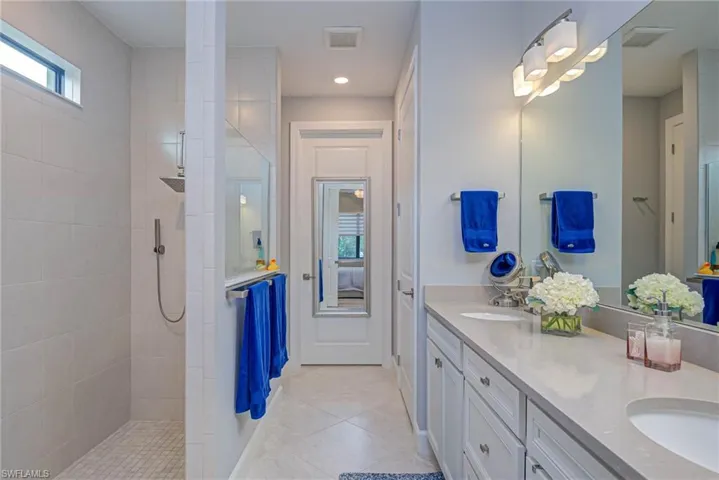 Bathroom with tile patterned floors, tiled shower, and vanity