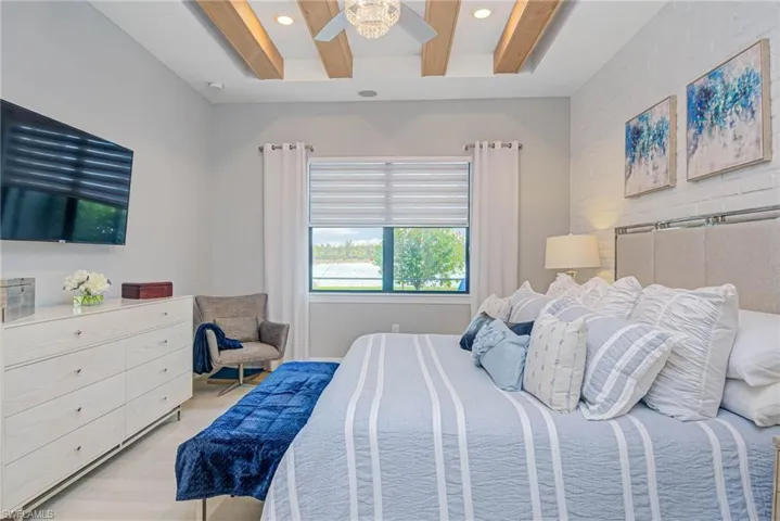 Primary bedroom with beam ceiling and white brick accent wall