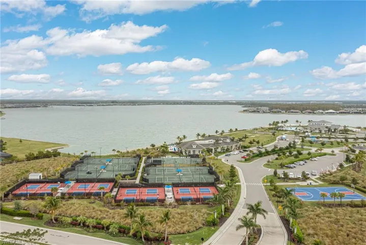 Aerial view of tennis, pickleball, and basketball court featuring a lake view