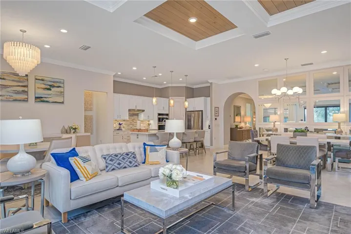 Living room featuring ornamental molding, wood ceiling, and an inviting chandelier