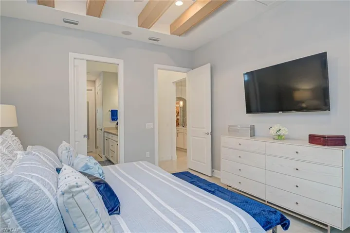 Primary bedroom with ensuite bathroom and beam ceiling