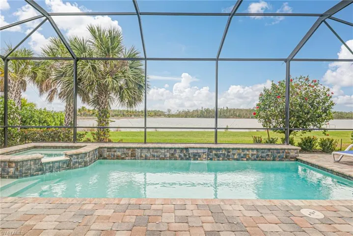 View of swimming pool featuring glass enclosure, a patio area, and an in ground hot tub