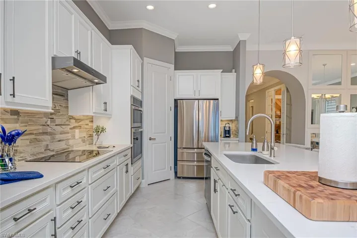 Kitchen with white cabinetry, sink, stainless steel appliances, and pendant lighting