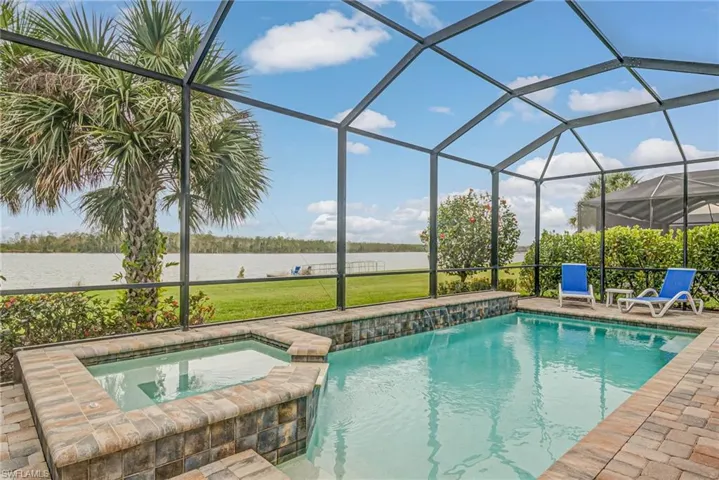 View of swimming pool with a lanai, a patio area, a water view, and an in ground hot tub