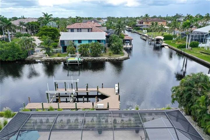 Dock area with boat lift, a water view, and a lanai