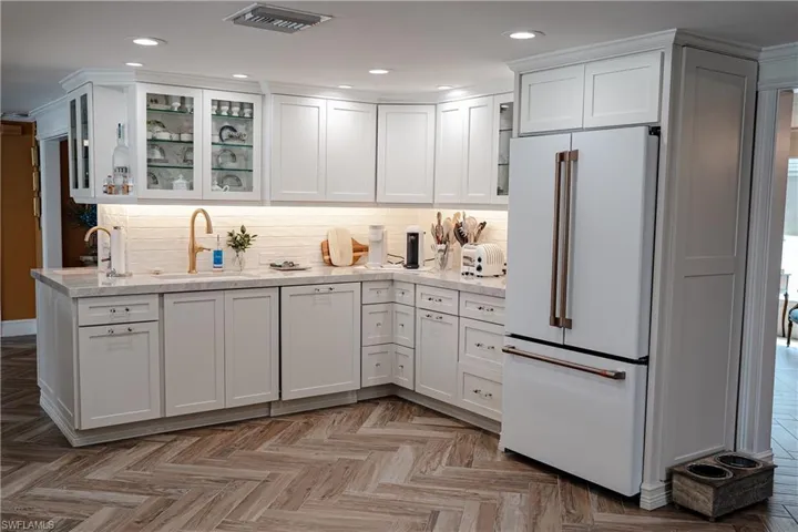 Kitchen with freestanding refrigerator, glass fronted cabinets, white cabinetry, recessed lighting, and parquet floors