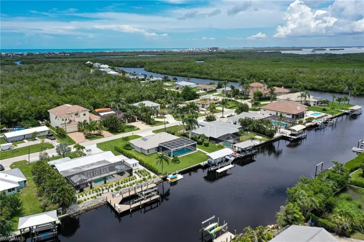 Aerial perspective of suburban area featuring a large body of water and a heavily wooded area