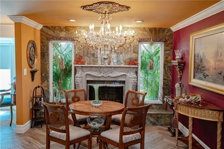 Dining space featuring crown molding, parquet flooring, a fireplace, and a chandelier