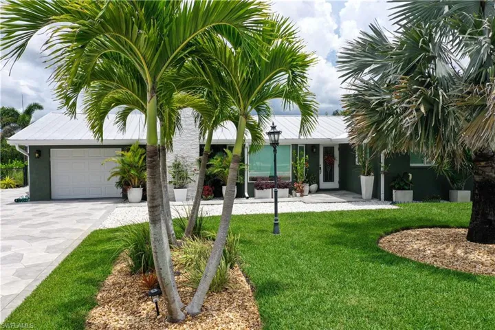 View of grassy yard with a garage and driveway