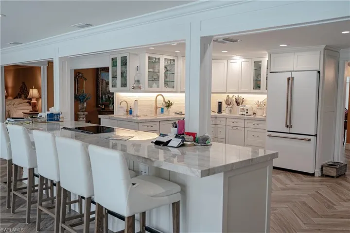 Kitchen with glass insert cabinets, white cabinetry, high end fridge, parquet flooring, and recessed lighting