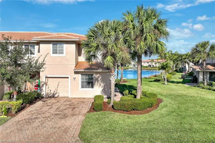 View of front facade with a tile roof, a front yard, stucco siding, decorative driveway, and an attached garage