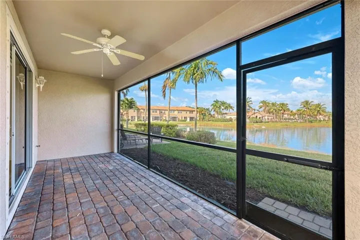 Unfurnished sunroom with a water view, a ceiling fan, and a residential view