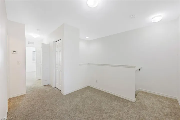 Empty room with light colored carpet and baseboards