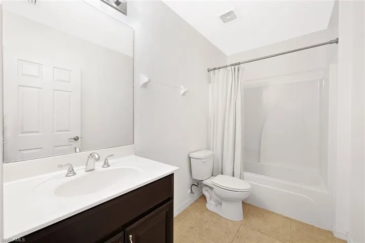 Bathroom with vanity, light tile patterned flooring, and shower / bath combination with curtain