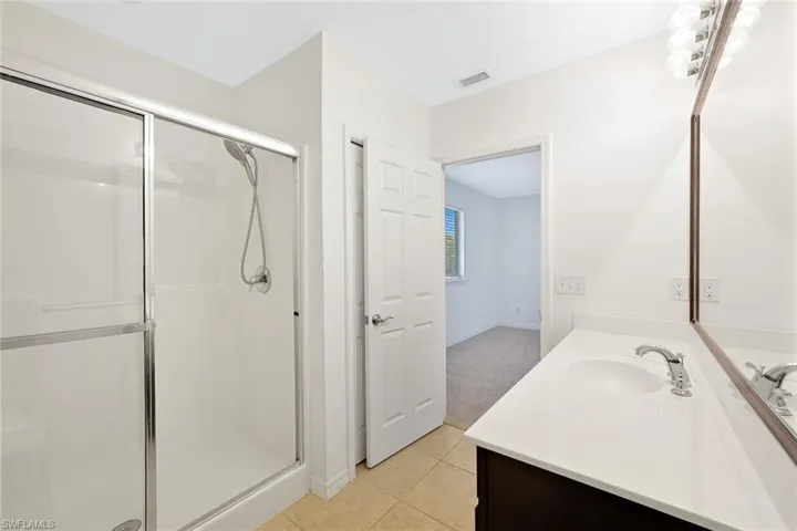 Full bath with vanity, a stall shower, and light tile patterned floors