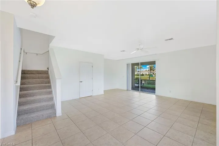 Unfurnished room featuring stairway, light tile patterned floors, and ceiling fan