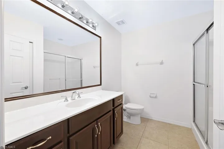 Bathroom featuring a shower stall, vanity, and light tile patterned floors