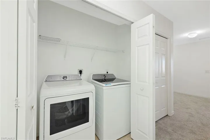 Laundry area with light carpet and washer and clothes dryer